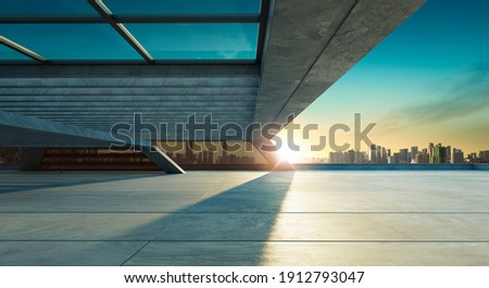 Perspective view of empty concrete floor and modern rooftop building with sunset cityscape scene. Mixed media