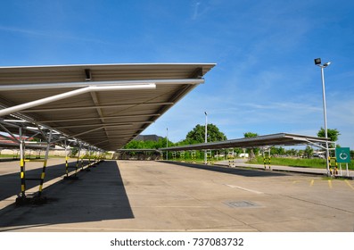 Perspective view of empty outdoor parking lot and metal sheet roof, metal structure with shadow and blue sky background
