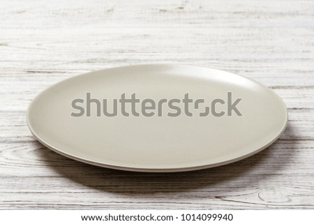 Perspective view. Empty white plate on wooden background.