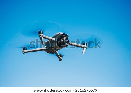 Perspective view of a high tech camera drone maneuvering in the bright blue sky at daytime