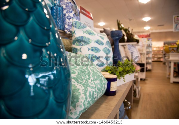 Perspective view of interior home décor\
store with pillows, candles and mantle pieces for\
sale.