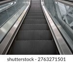 A perspective view looking down a long silver escalator
