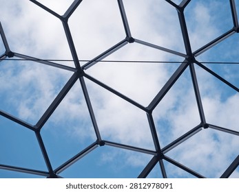 Perspective view of a modern architectural dome with a geometric glass and steel framework against a bright sky, ideal for technology and construction concepts.