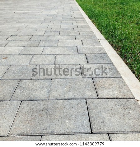 Perspective View Monotone Gray Brick Stone Pavement on The Ground for Street Road. Sidewalk, Driveway, Pavers, tile, green grass 
