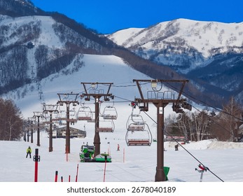 Perspective view of multiple ski lifts on a wide piste (Tsugaike Kogen, Hakuba, Nagano, Japan)