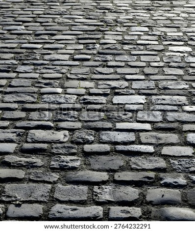 Perspective view of old gray cobblestone street with rough stone pavement texture, suitable for background, urban, and architectural concepts