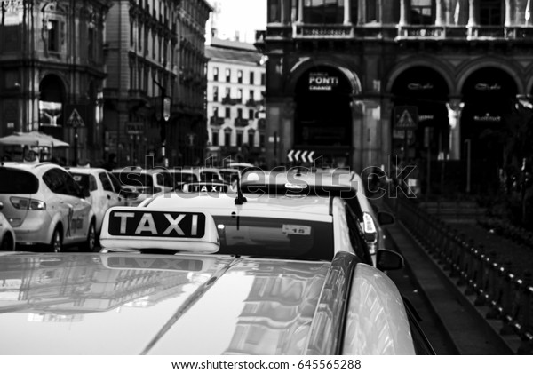 a perspective\
view on parked taxi in a row in Milan city. (black and white\
vwrsion) italy-milan 19 april 2017\

