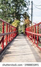 Perspective View Of Red Iron Suspension Pedestrian Bridge In Green Forest Wood Park. Nature Landscape No People Background. Direction, Moving Forward, Future Development Concept