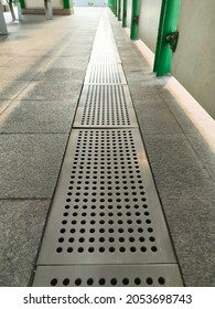 Perspective view of stainless steel rail drain water, sewer round hole texture on train station.