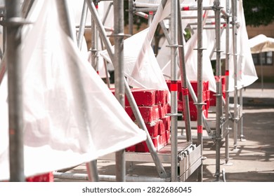 Perspective view of temporary modular scaffolding installation with white fabric covers and red counterweight ballast