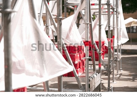 Perspective view of temporary modular scaffolding installation with white fabric covers and red counterweight ballast