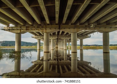 Perspective view of underside of bridge with the bridge reflection in the river below. 