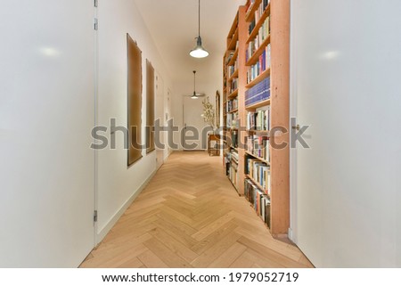 Perspective view of white apartment corridor with parquet floor and wooden bookcases with books under glowing lamps