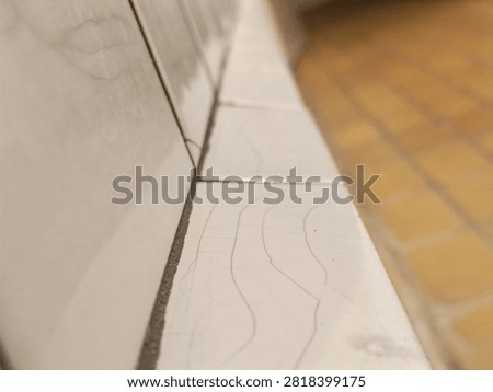 Perspective view of white ceramic tiles with fine crazing and hairline cracks on the edge.