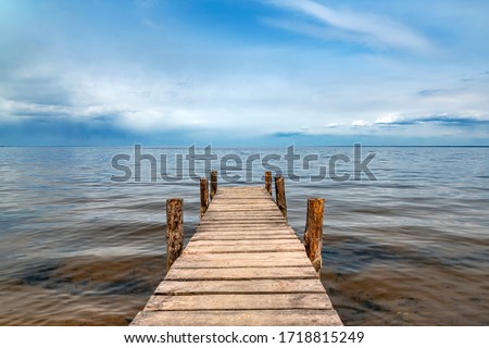 Perspective view of wooden pier at lake. Small bridge in water