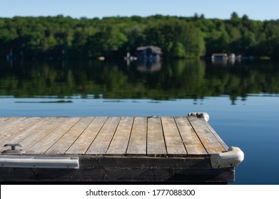 Perspective of a wooden dock on a calm lake in Muskoka, Ontario Canada.