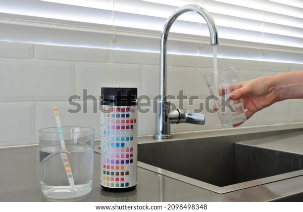 PERTH, WA - DEC\
23 2021:Drinking water test kit on home kitchen counter surface\
while a person filing a glass cup of tap water.About 1 to 2 billion\
people lack safe drinking\
water.
