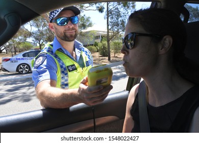 PERTH, WA - OCT 27 2019:Australian traffic police officer using breathalyzer on woman driver during field sobriety testing.Traffic accidents are predominantly caused by Impaired driving
