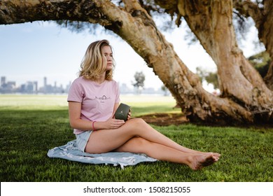 Perth, Western Australia - 14th September, 2019 : Beautiful Girl Drinking Coffee From A Reusable Eco Friendly Cup On The South Perth Foreshore. Early Morning In A Park With The City In The Background.