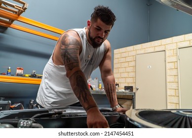 Perth, Western Australia - April 16th 2022: My Mechanic Friend Opening Up The Bonnet Of His Custom Made Car To Repair The Engine And Tightening Screws