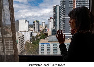 Perth, Western Australia, Australia - November 11, 2020: Woman gazing out to city while in strict hotel quarantine during COVID-19 pandemic