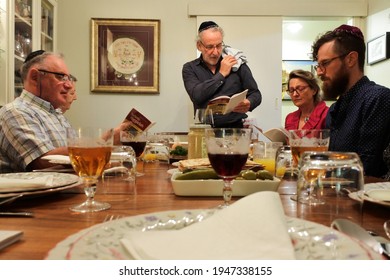 PERTH,WA - MAR 28 2021:Jewish family reading the Haggadah during Passover Jewish holiday.Passover marks the date when God "passed over" the houses of the Israelites during the last of the ten plagues.