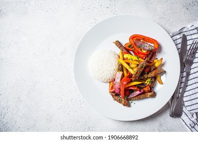 Peruvian cuisine concept. Lomo saltado - fried pieces of beef with peppers, onions and potatoes on a white plate.