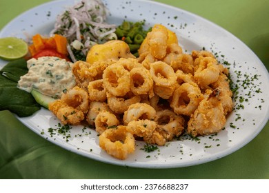 El chicharrón de Calamar peruano es un delicioso plato con calamares fritos, a menudo servidos como aperitivo o tentempié. Es conocida por su textura crujiente y su sazonado sabroso. 
