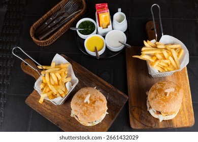 Peruvian Gastronomy, A table with two plates of hamburgers and two plates of french fries. The hamburgers are on wooden boards and the fries are in baskets. The table is set for a meal