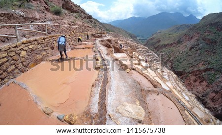 Peruvian workers at Maras salt mine (salt evaporation ponds) terraces in Sacred Valley, Cusco, Peru. One of the major tourist attractions in Urubamba Valley. Manual labor is used for salt extraction.