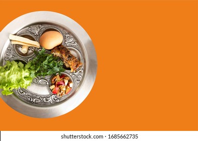 Pesach Plate. Jewish Seder On The Occasion Of Passover Festival. Traditional Seder Holiday Plate Isolated On An Orange Background.