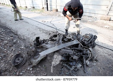 PESHAWAR, PAKISTAN - NOV 02: A policeman inspects a damaged vehicle engine which was destroyed in explosion after bomb explosion at the site in the outskirts on November 02, 2011in Peshawar.