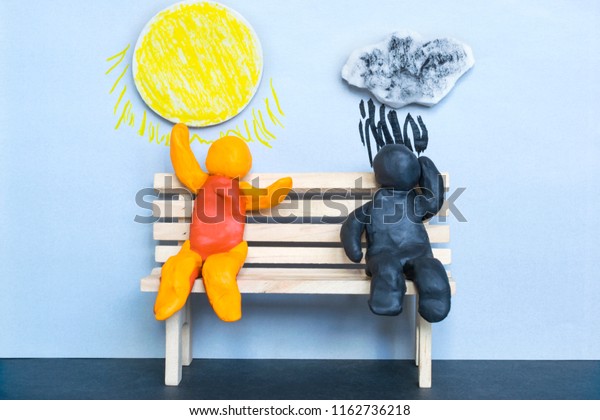 Pessimism and optimism concept, sad and\
happy plasticine men under the cloudy and sunny sky.\
