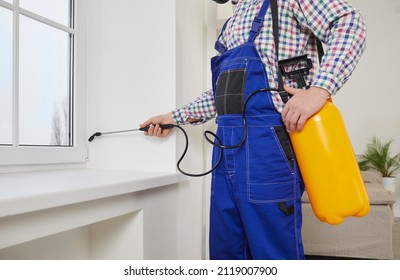 Pest control guy spraying poisonous gas or liquid on a windowsill at home. Male exterminator in overall uniform workwear spraying insecticide over a modern white window and sill inside the house