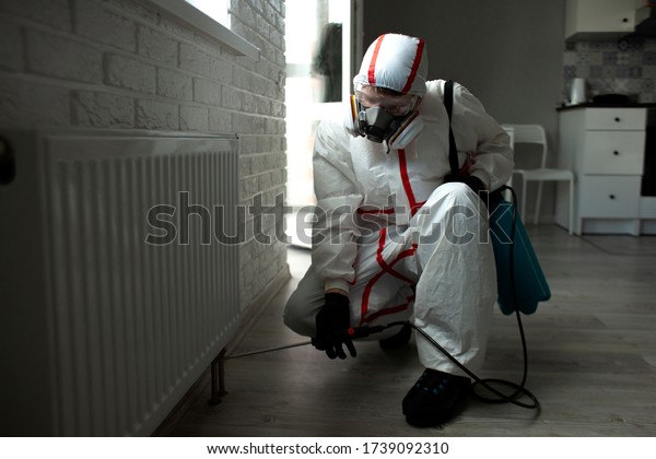 pest control. a man in a chemical suit\
disinfects the room from rodents and insects, a sanitary worker\
with a spray on the background of the\
apartment
