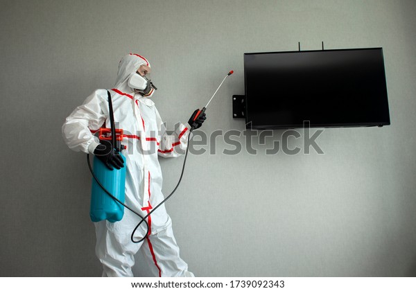 pest control. a man in a chemical suit\
disinfects the room from rodents and insects, a sanitary worker\
with a spray on the background of the\
apartment