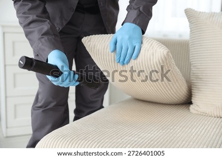 Pest control worker examining sofa with flashlight indoors, closeup