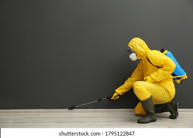 Pest control worker in protective suit spraying pesticide near black wall indoors. Space for text - Shutterstock ID 1795122847