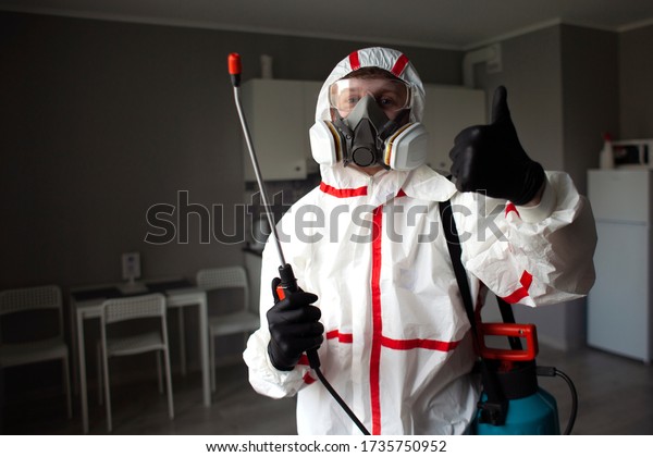 pest control. Worker in a protective suit shows\
like, portrait of a sanitary service man against the background of\
the room, copy space