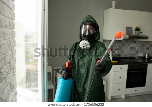 pest\
control. A worker in a protective suit cleans the shelves in the\
kitchen from cockroaches and ants with a spray, the sanitary\
service disinfects the room with a chemical\
agent