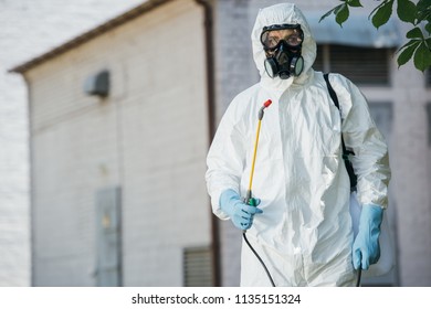 Pest Control Worker In Respirator Holding Sprayer 