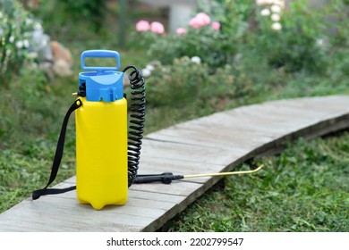 A pesticide sprayer stands on a wooden path in the garden. Against the background of a flower bed. Copy space. - Shutterstock ID 2202799547