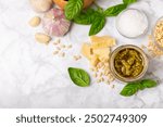 Pesto. Italian basil pesto sauce on a textured wooden background. Ingredient for pesto sauce: fresh basil, pine nuts, Parmesan cheese and olive oil. Space for text.Copy space.