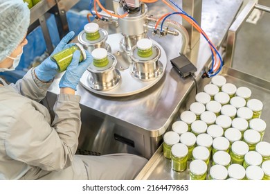 Pesto Sauce With Basil Industrial Process. Factory Worker Working On Vacuum Sealing Machine For Canned Food. Production Of Pesto Sauce. Vacuum Seamer For Cylindrical Cans Of Rotary Type