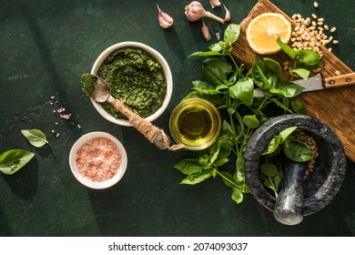 Pesto Sauce In Bowl With Ingredients On Rustic Green Table. Traditional Italian Pesto Recipe For Making Fettuccine, Pasta, Bruschetta.