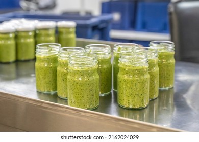 Pesto sauce Industrial process. High quality sauce production. Green pesto sauce in open jars on a food factory table. Italian basil taste in Pesto sauce - Shutterstock ID 2162024029