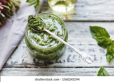 Pesto Sauce In Vintage Spoon On Glass Jar Of Pesto Sauce With Ingredients,fettuccine On Rustic White Wooden Table. Traditional Italian Pesto Recipe For Making Pasta, Spaghetti, Bruschetta,pizza.