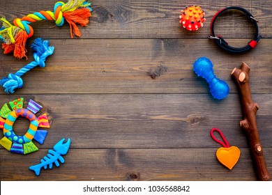 Pet accessories. Toys near collar on dark wooden background top view copy space