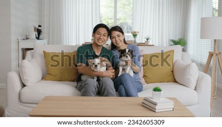 Pet as baby child in Gen Z asia young adult couple hug cuddle dog sit at home sofa couch looking at camera. Selfie with small cute little chihuahua owner relax family cozy life love puppy animal lover