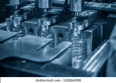 The PET bottles in the automatic blowing mold processing machine in the light blue scene. The drinking water factory production process by automatic blowing  machine .